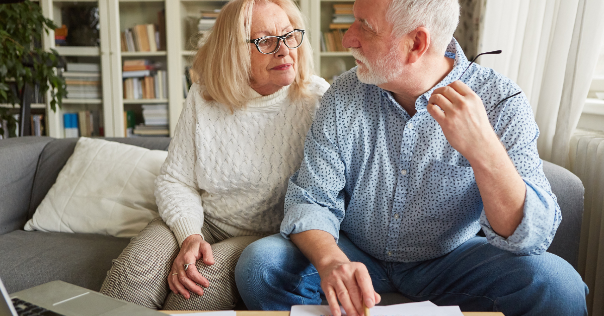 Senior couple discussing finances at home, reviewing documents together