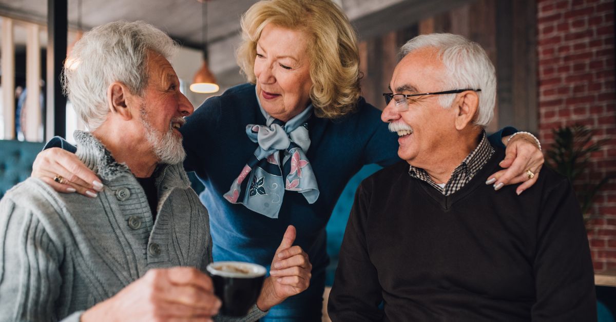 Happy senior woman enjoying conversation with two older men at a café