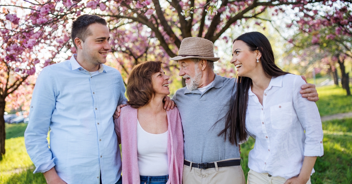 Smiling multigenerational family standing outdoors under blossoming trees, symbolizing joy, connection, and blending families after 50.