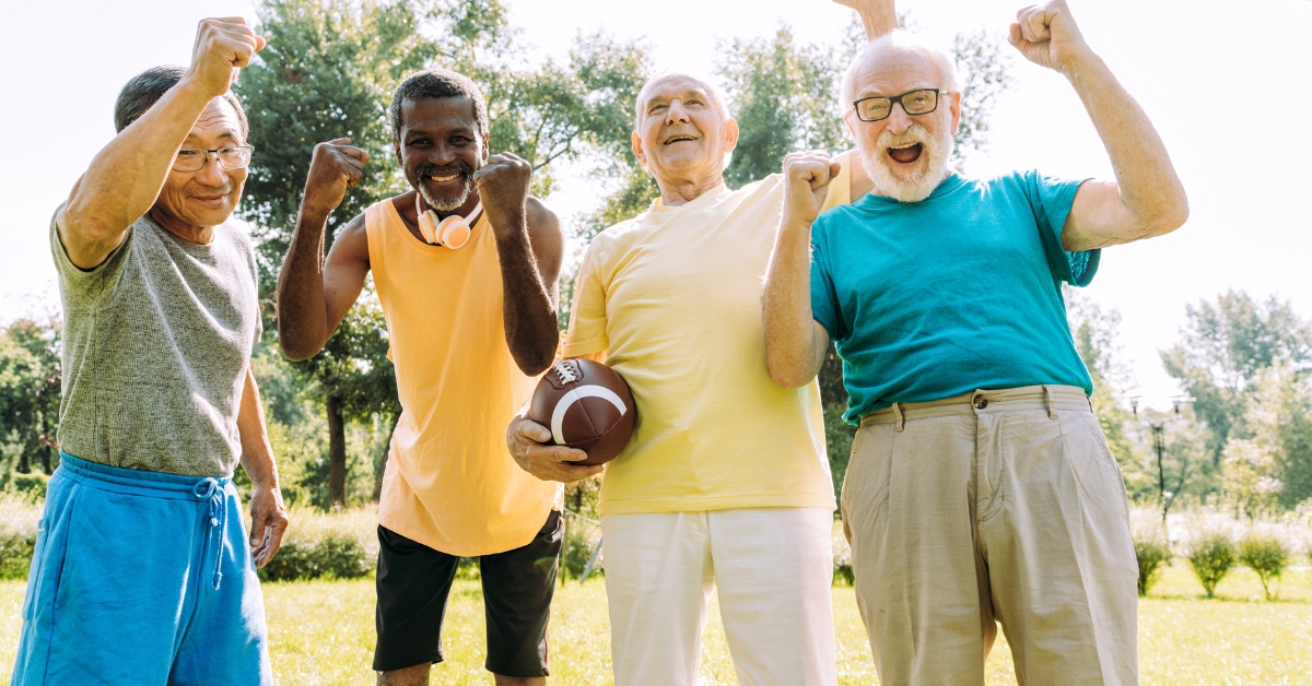 Developing a Healthy Dating Mindset For Single Seniors - Mature Singles Finding Love A group of four senior men outdoors, dressed in colorful casual sportswear, smiling and celebrating with raised fists while holding a football, symbolizing active and joyful senior living.