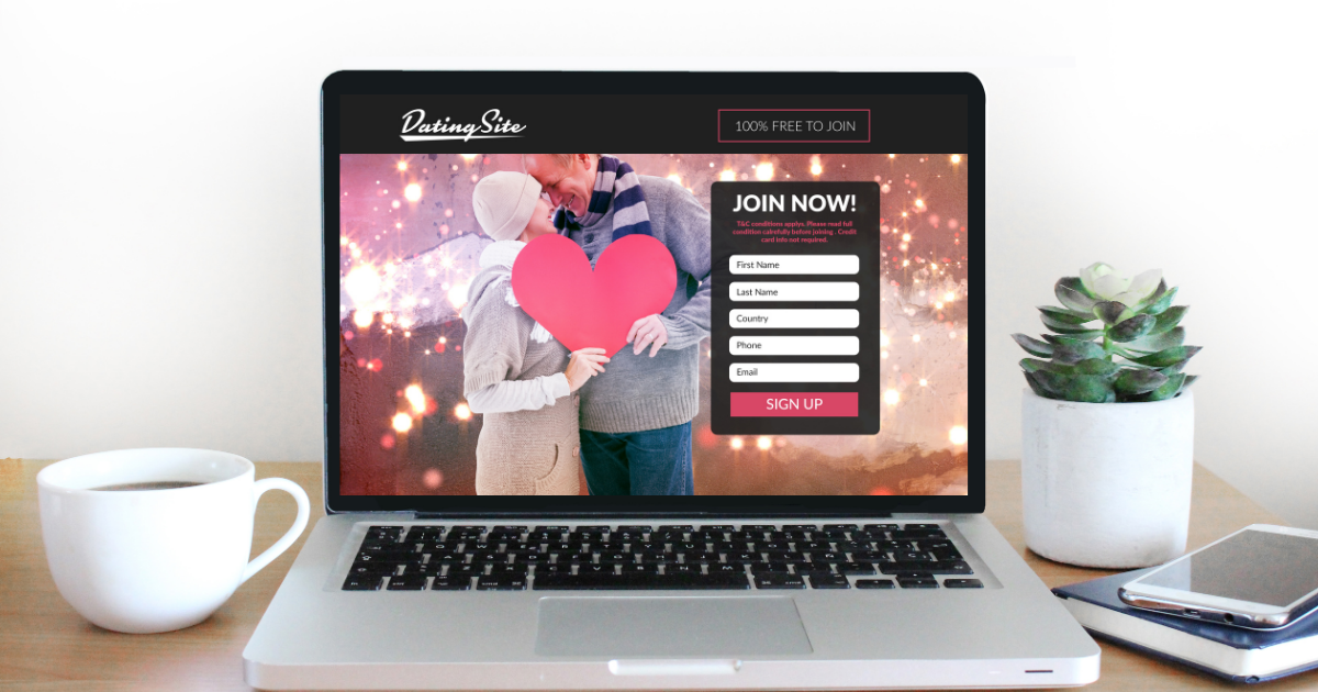 Exploring Senior Dating Sites_ A Guide - Mature Singles Finding Love A laptop displaying a dating site homepage with a signup form titled 'Join Now!' and a background image of a senior couple holding a heart. The interface promotes a '100% Free to Join' feature. The setup includes a cup of coffee, a potted plant, and a smartphone on the desk.