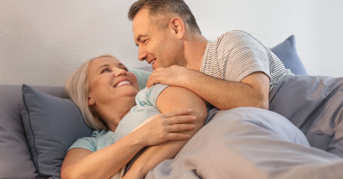 Happy middle-aged couple cuddling in bed, sharing an intimate and affectionate moment