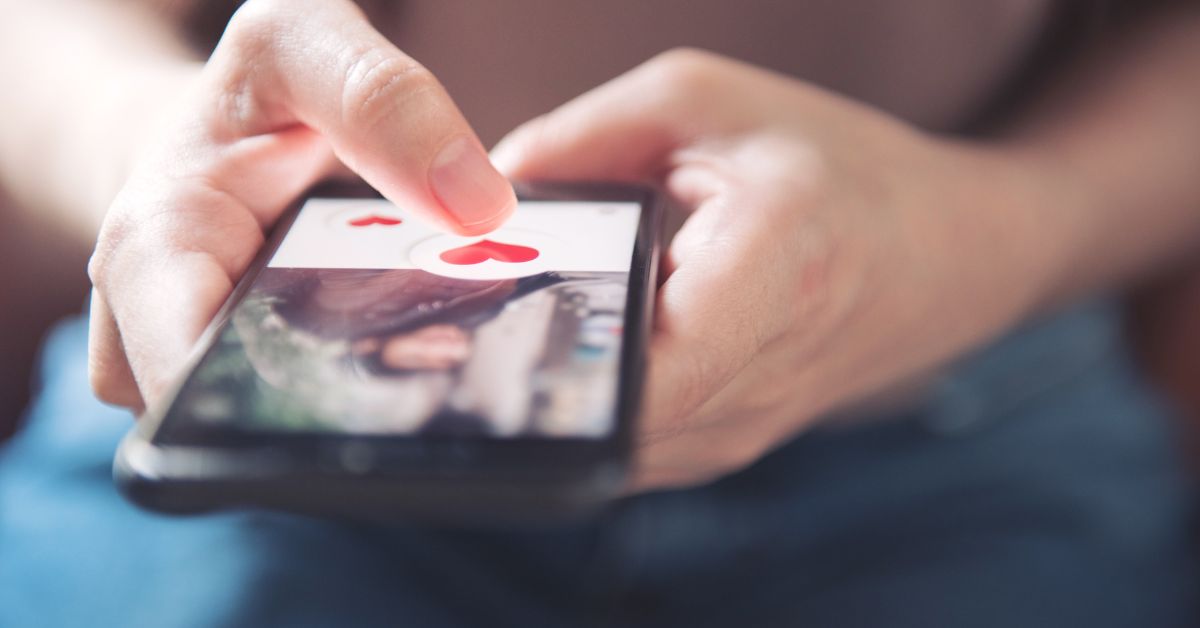 Close-up of a person using a dating app on a smartphone, tapping the heart icon to like a profile, symbolizing online dating and technology in relationships