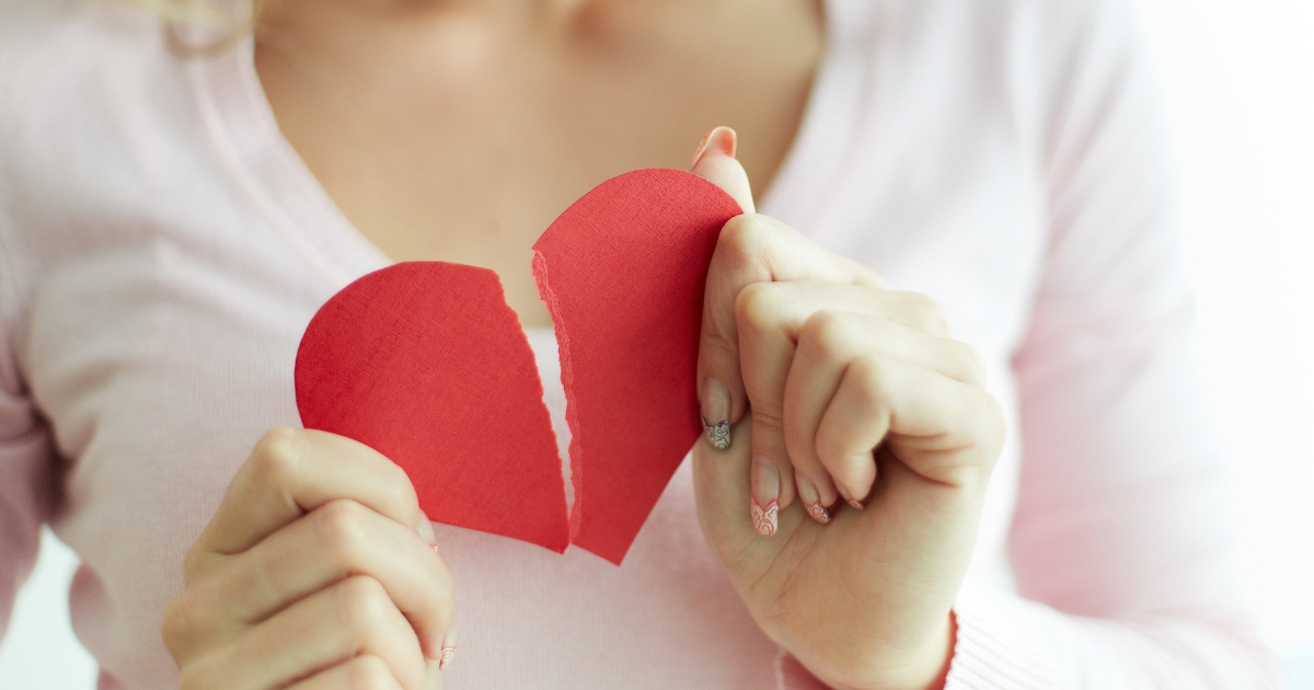 How To End A Relationship Without Breaking Someones Heart - Mature Singles Finding Love Woman gently holding a torn paper heart, symbolizing a breakup and the emotional process of ending a relationship with care and compassion.