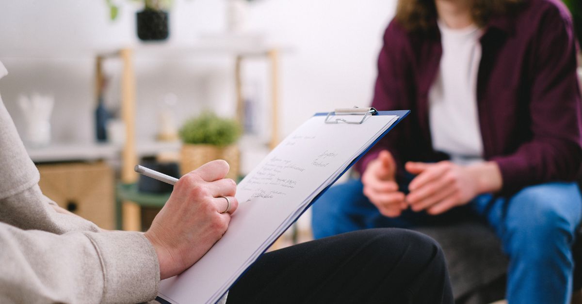Close-up of therapist taking notes during a counseling session, representing professional sex coaching and support for later-in-life intimacy exploration.