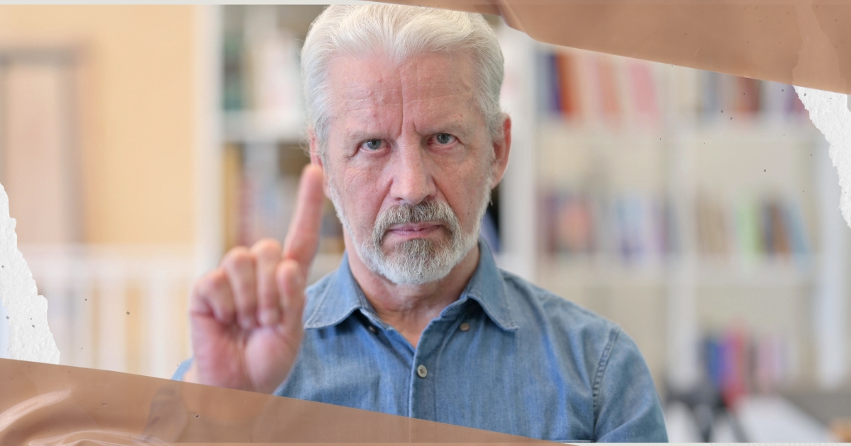 Serious older man raising his index finger as a warning gesture, symbolizing awareness and caution in identifying red flags in relationships after 50.