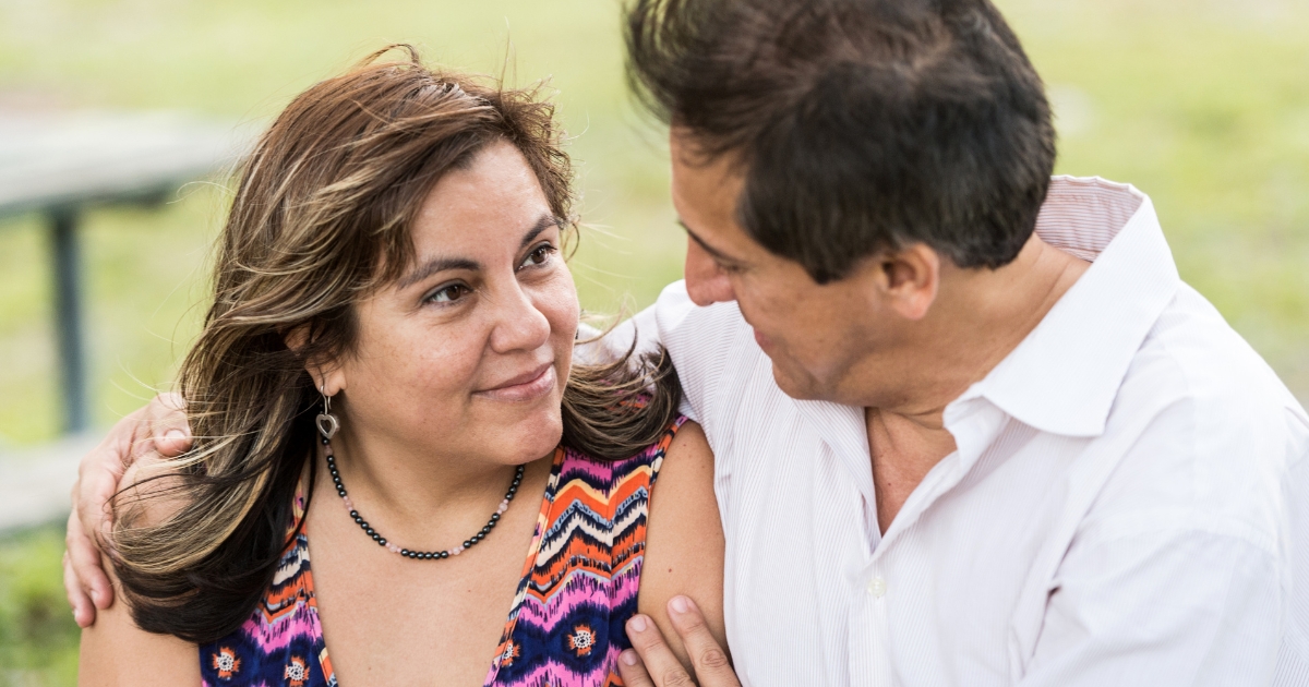Middle-aged couple sitting outdoors, looking into each other’s eyes with affection — representing emotional connection and comfort on a first date.