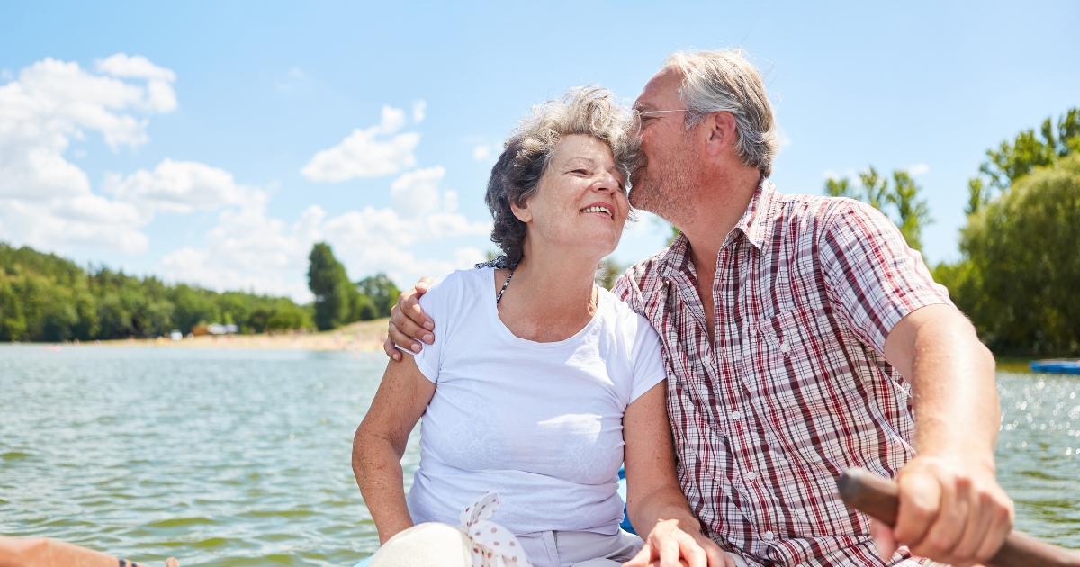 Happy senior couple enjoying a romantic boat ride on a sunny day, representing love and connection in midlife relationships.
