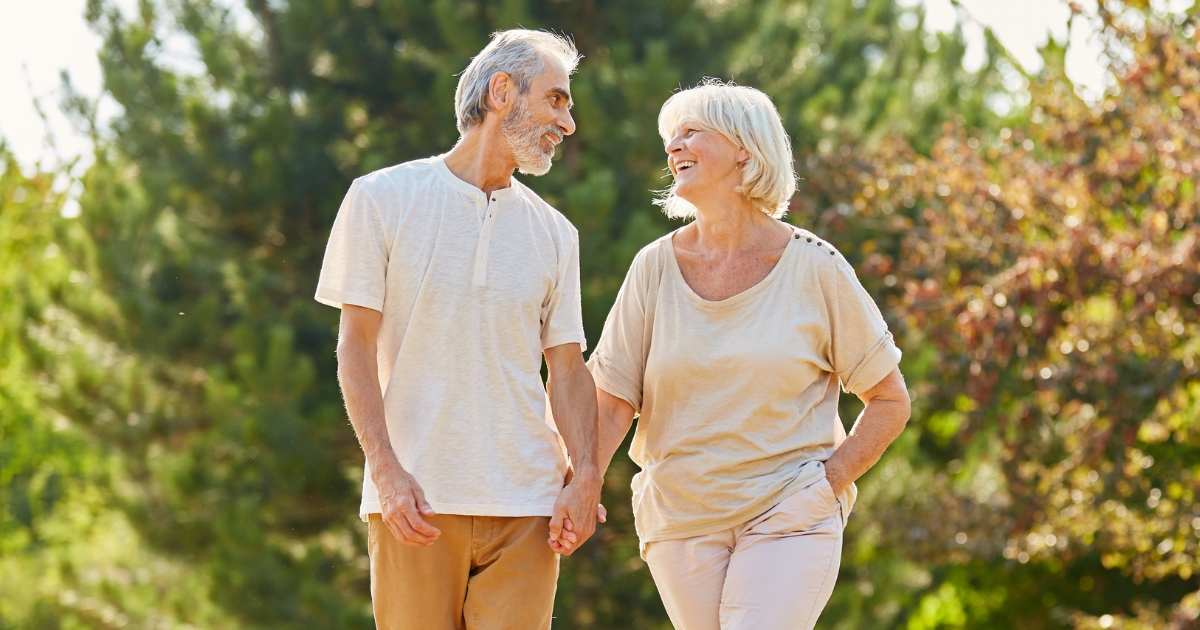 Happy senior couple holding hands and walking outdoors in a park — symbolizing emotional readiness, dating after 50, and finding joy in new relationships.