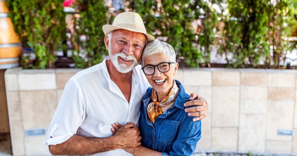 Happy senior couple smiling and embracing outdoors, symbolizing trust, love, and companionship in relationships after 50.