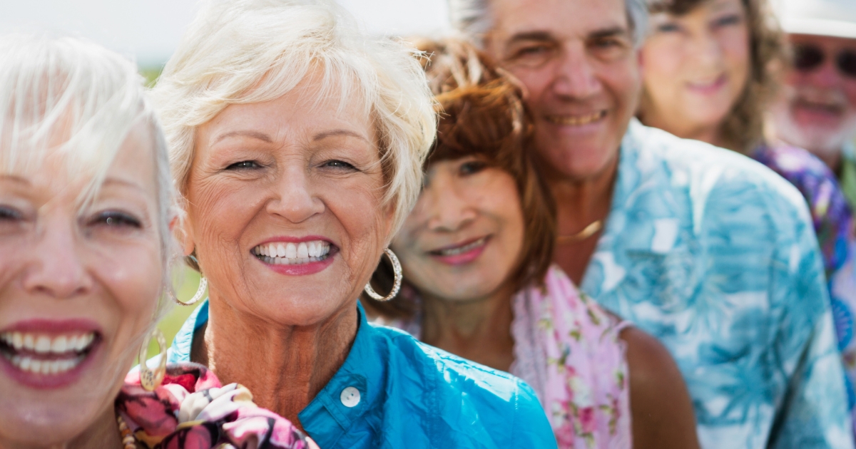 Group of smiling older adults enjoying time together outdoors, representing friendship and social connection after 50.