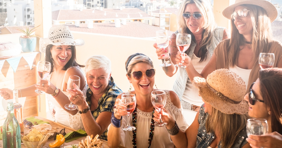 Group of smiling women over 50 enjoying wine together at a social gathering