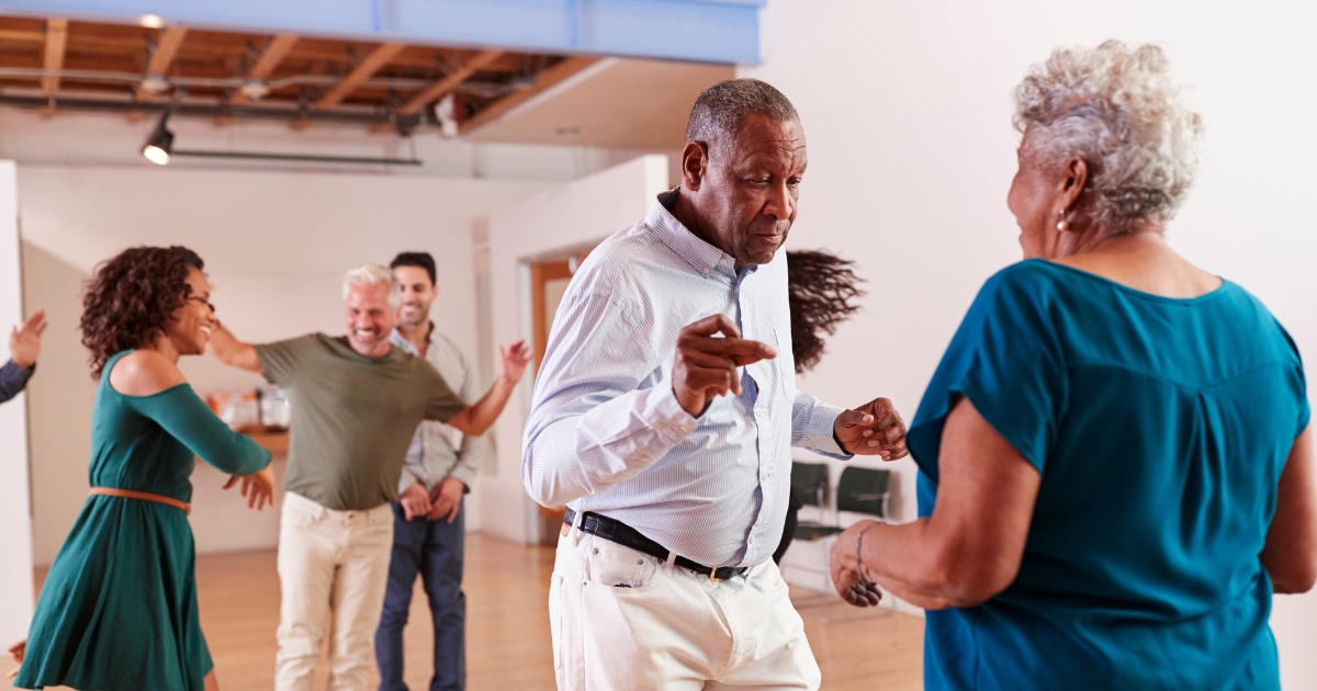 Happy older and younger adults dancing together at a social event, symbolizing connection, joy, and navigating relationships across generations.