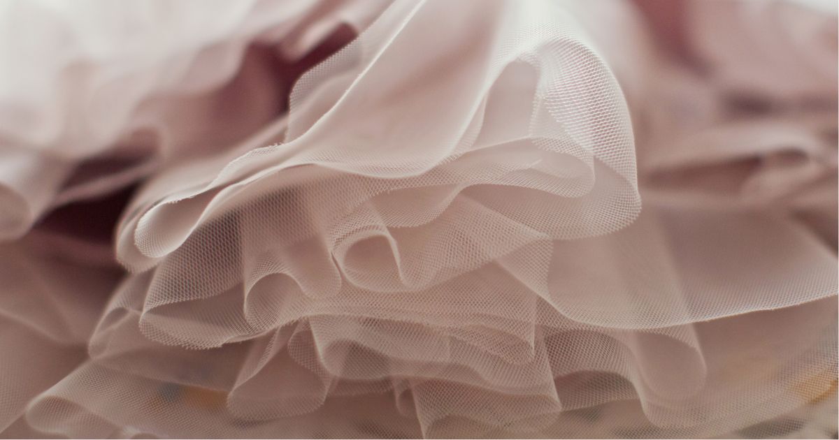Close-up of delicate pink tulle fabric with soft folds and texture.