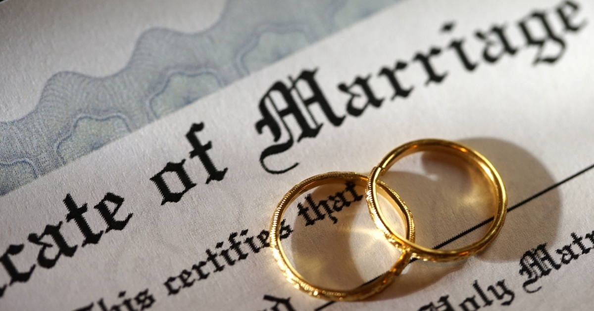 Close-up of two gold wedding rings resting on a marriage certificate document.
