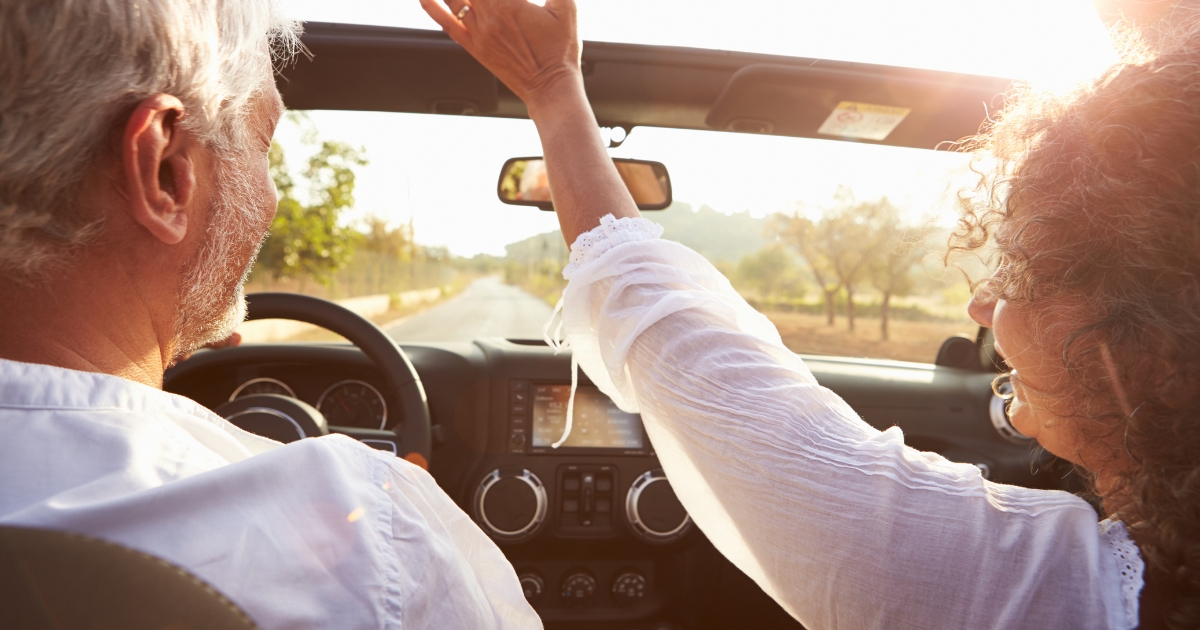 Happy mature couple driving in a convertible with the top down at sunset, symbolizing quality time in relationships, emotional connection, and making meaningful memories together after 50.