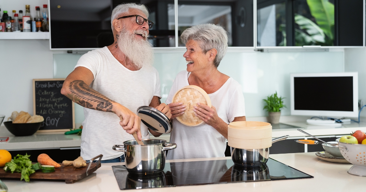 Happy senior couple cooking together in a modern kitchen, smiling and enjoying quality time—representing love, companionship, and healthy relationships after 60.