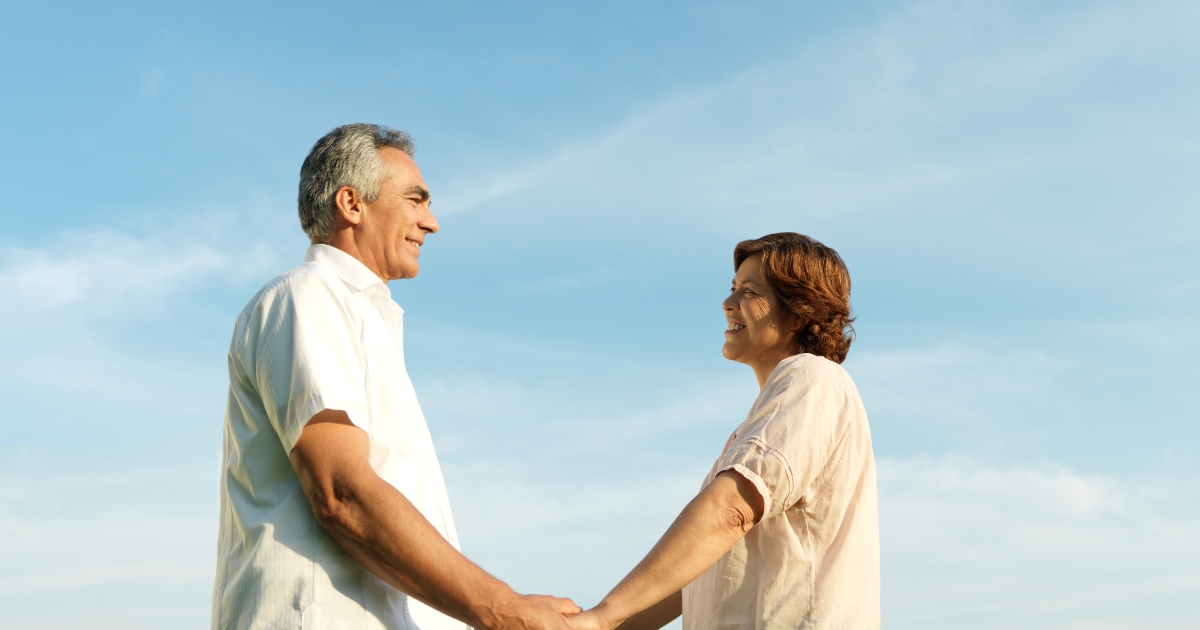 Happy mature couple holding hands and smiling outdoors after finding love again