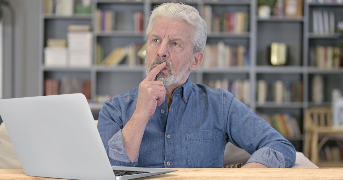 Thoughtful mature man looking at laptop, wondering about online dating and ghosting