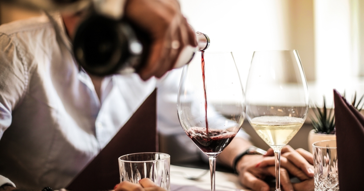 Pouring red wine at romantic dinner date, symbolizing senior dating confidence