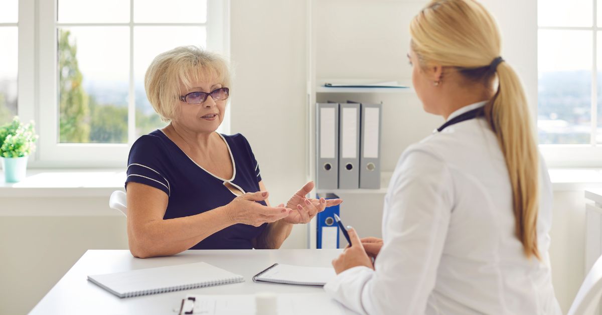 Senior woman having a consultation with a female doctor in a bright medical office, discussing health concerns related to painful sex or intimate discomfort.
