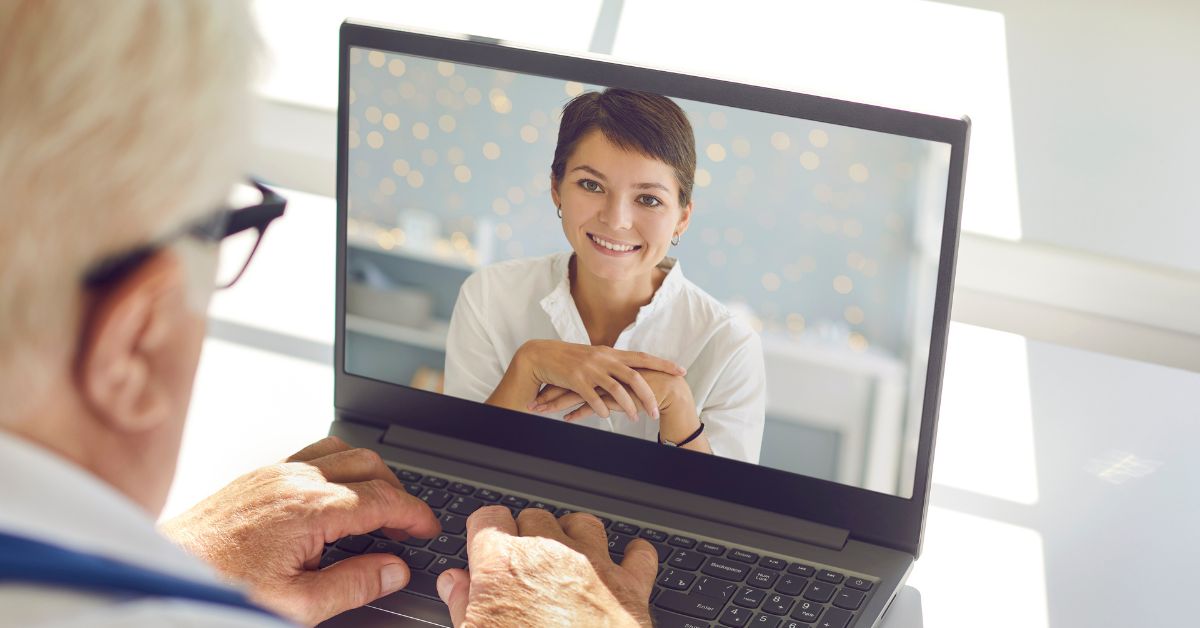 Senior man using a laptop for a video call with a smiling woman, highlighting technology use for mature adults.