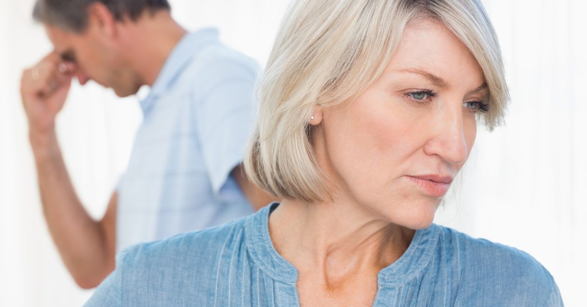 Is Your Partner Immature_ How It Can Affect Your Relationship - Mature Singles Finding Love Frustrated middle-aged couple facing relationship tension, with the woman looking away and the man in the background holding his head in stress.