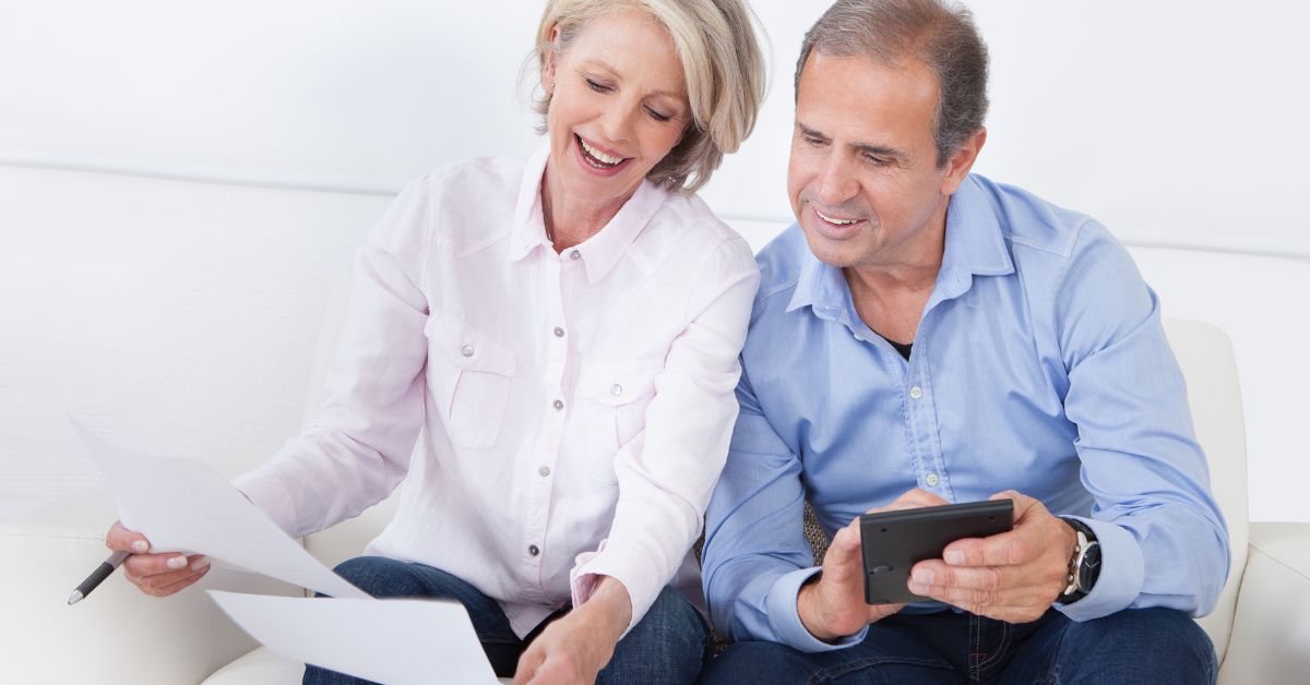 Older couple reviewing financial documents and using calculator – budgeting after 50