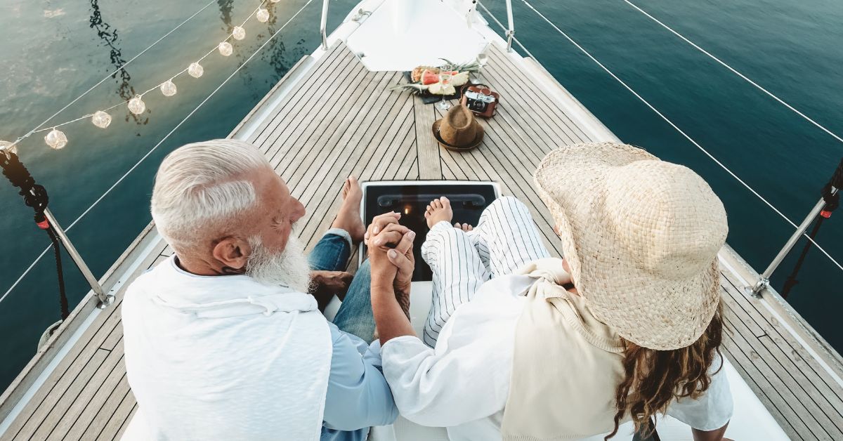Senior couple holding hands on a boat, enjoying romantic sunset cruise