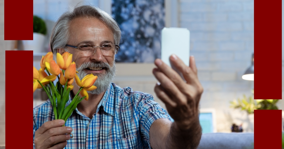 Smiling older man holding a bouquet of tulips and taking a selfie, representing modern dating etiquette and romantic gestures for mature singles.