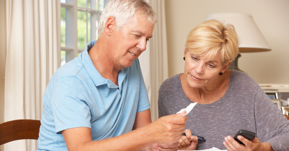 Shared Goals Shared Funds_ Tips for Combining Finances After Midlife - Mature Singles Finding Love Older couple reviewing financial documents together at home, representing combining finances after 50.