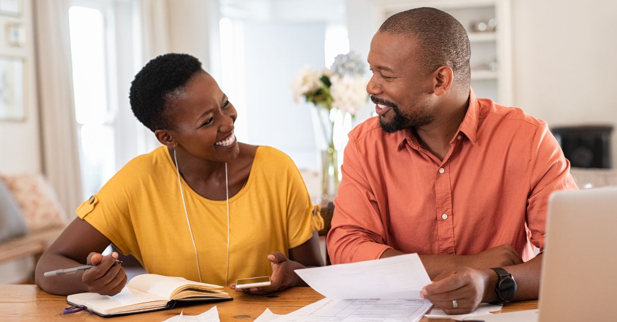 Happy couple budgeting together at home, symbolizing financial teamwork and relationship planning.