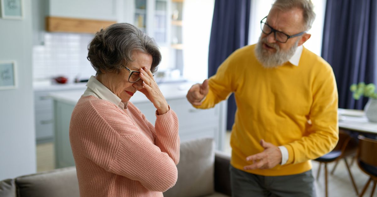 Older couple arguing at home with woman feeling stressed and man raising his voice