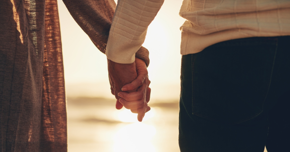 Silver Linings of Love_ Building Stronger Relationships After Loss - Mature Singles Finding Love Close-up of a couple holding hands at sunset, symbolizing emotional healing and rebuilding relationships after loss.