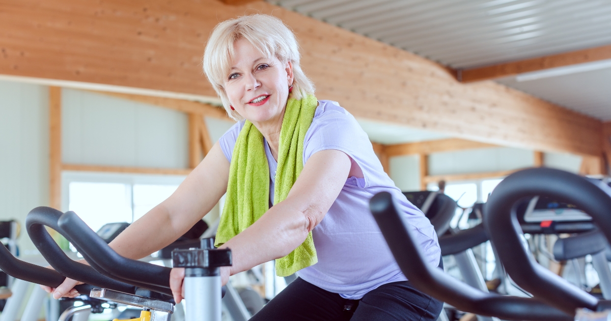 Strength Training and Fitness for Women Over 50_ Staying Active and Confident - Mature Singles Finding Love Active senior woman using stationary bike at gym, promoting fitness and strength training for women over 50.