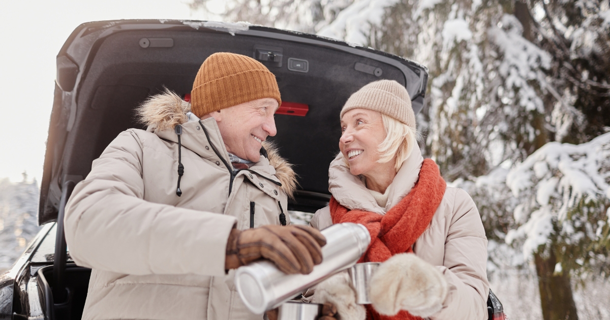Taking The Next Step_ Meeting Someone For The First Time After Messaging Online - Mature Singles Finding Love Happy senior couple on a winter date, sharing a warm drink from a thermos near their car in a snowy forest, enjoying a first meeting after online dating.