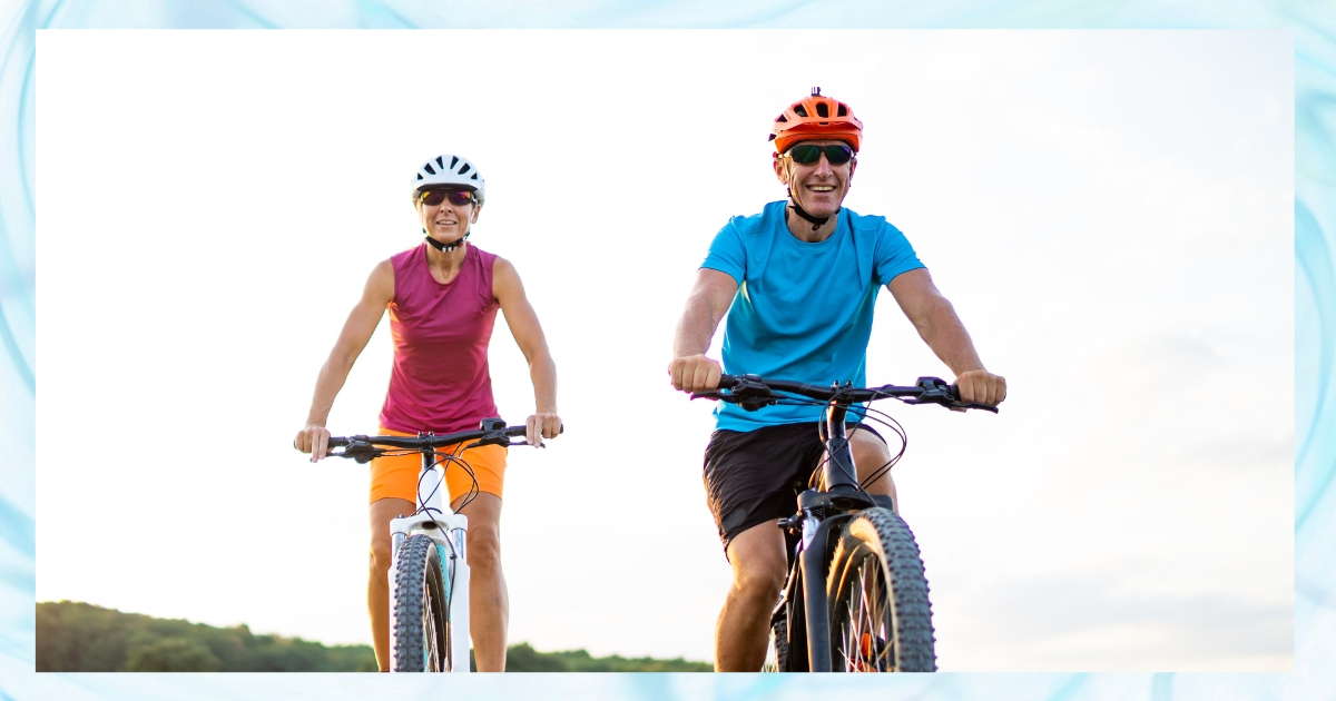 Smiling active older couple riding bicycles outdoors, representing the benefits of fitness and shared physical activity for love and relationships after 50.