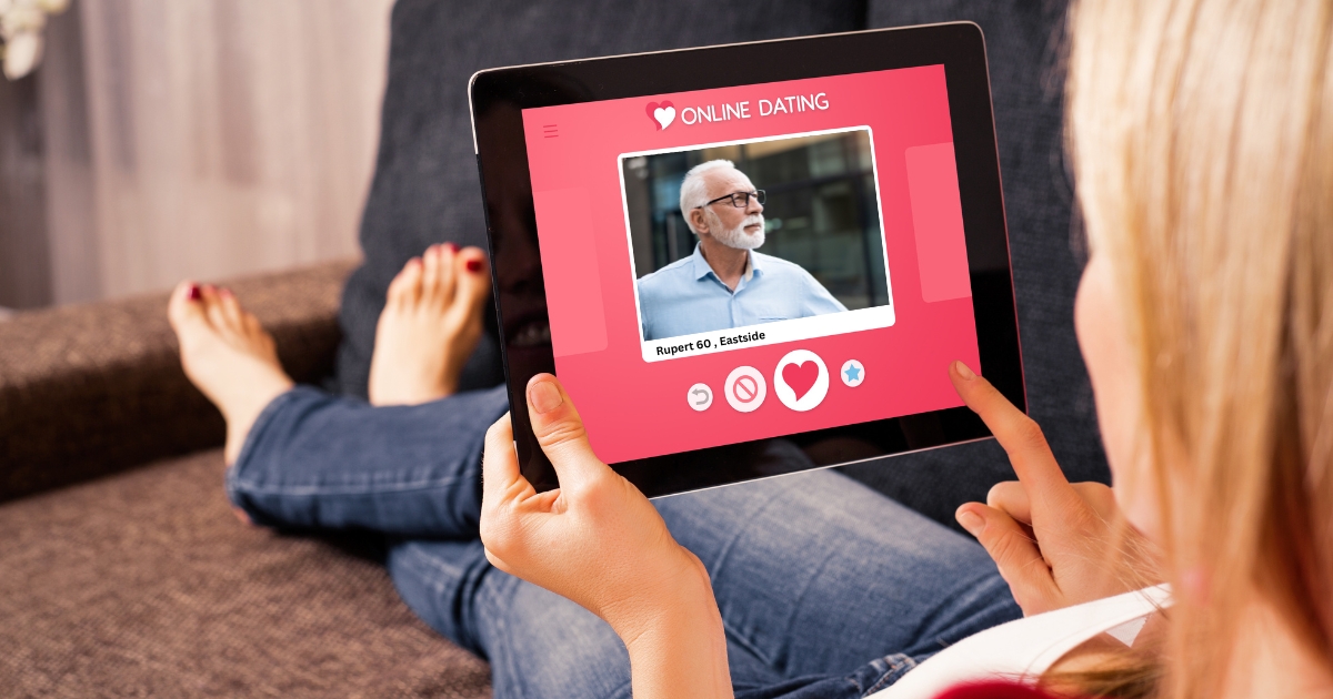 Woman using a tablet to browse an online dating profile of a mature man, illustrating online dating for singles over 50 and the importance of profile photos.