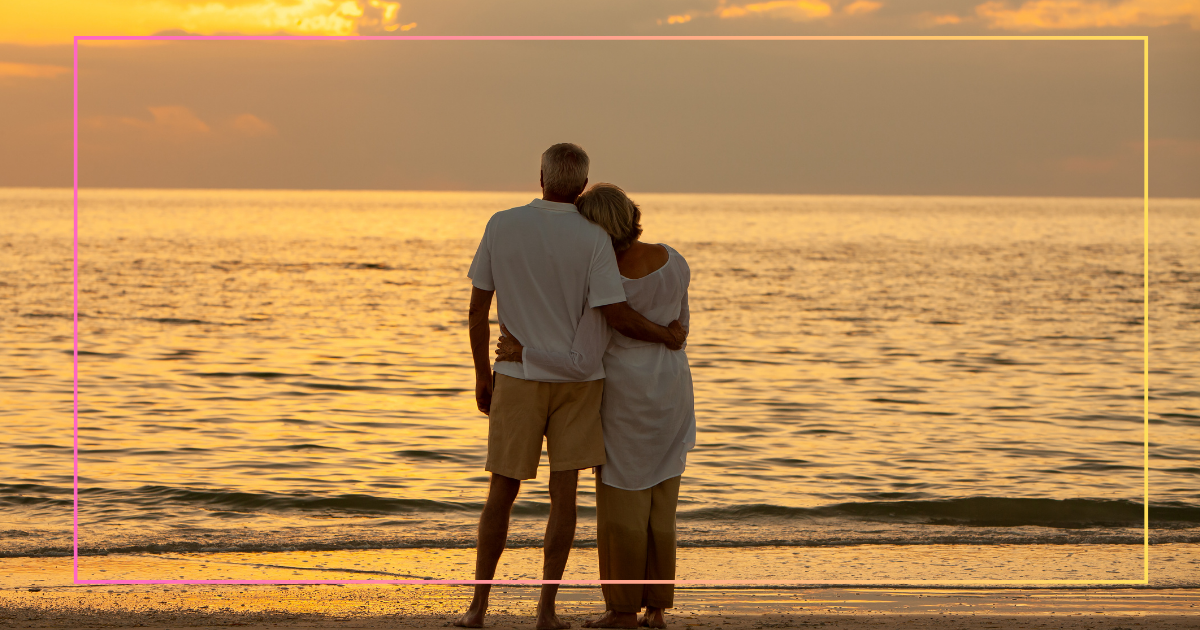 The Psychological Benefits of Dating in Your 50s - Mature Singles Finding Love A mature couple standing together on a beach at sunset, embracing while gazing at the ocean, symbolizing love and companionship