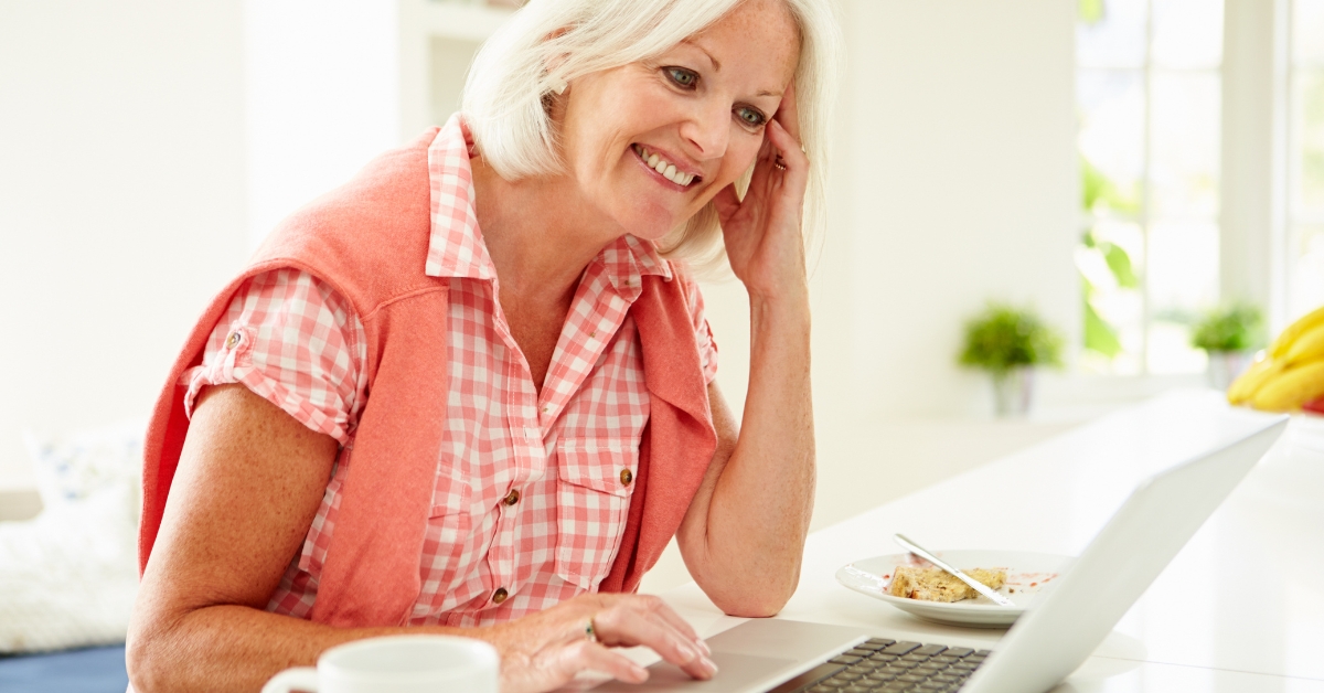 Top 10 First Message Tips for Online Dating Success - Mature Singles Finding Love Smiling older woman using a laptop for online dating, engaging in meaningful connections in her golden years.