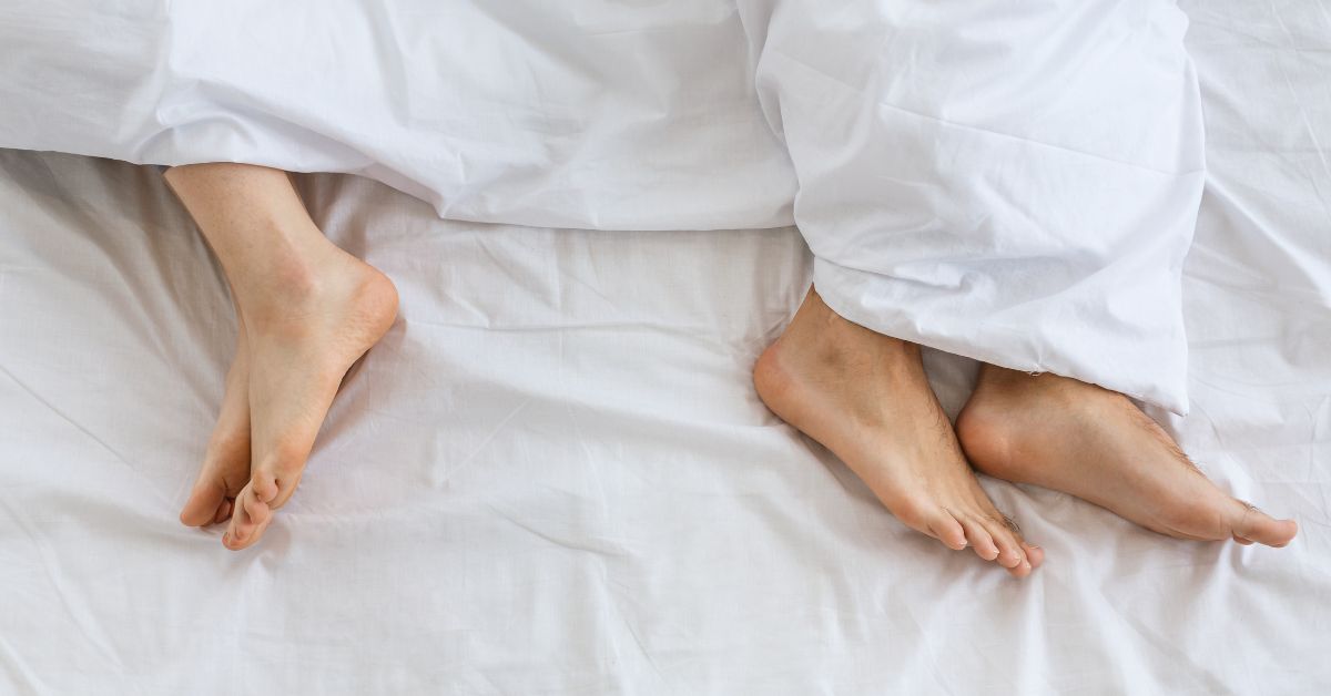 Under Pressure_ How Social Norms May Be Impacting Your Libido2 - Mature Singles Finding Love Couple’s feet under white sheets, symbolizing intimacy and connection
