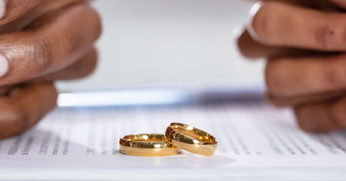 What Are The Most Common Reasons For Divorce - Mature Singles Finding Love Two wedding rings placed on divorce papers with hands in the background, symbolizing separation.