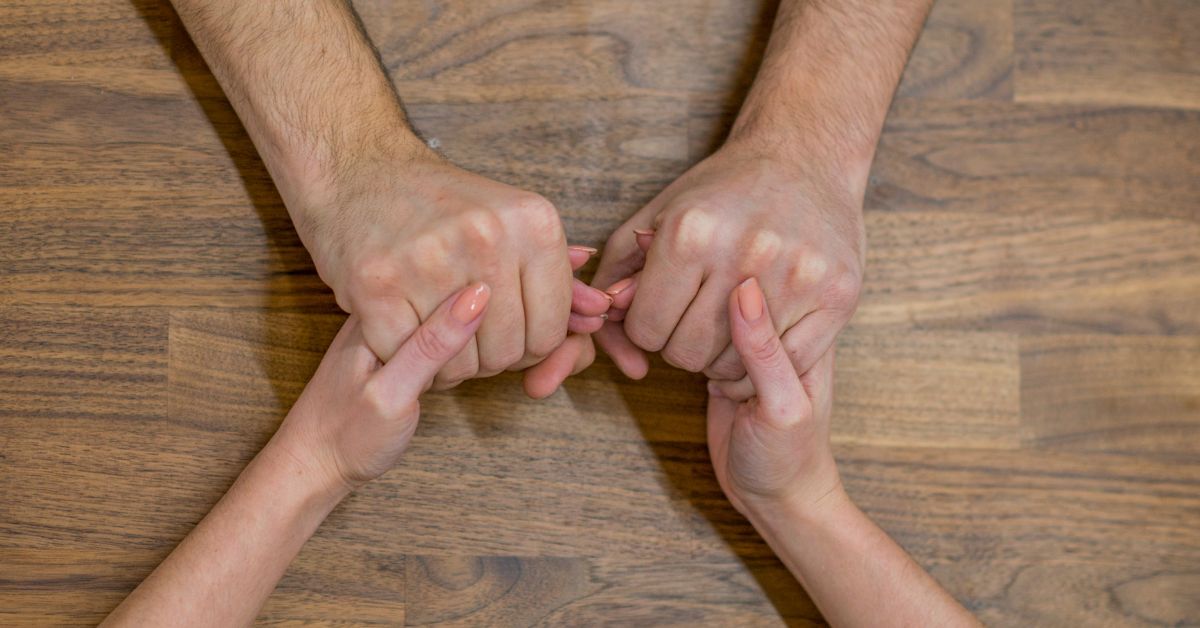 When Expectations Dont Align_ How to Work Towards Compromise and Growth Together - Mature Singles Finding Love Couple holding pinkies in a sign of connection and compromise on a wooden table