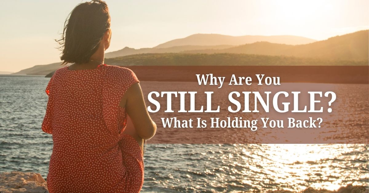 Why Are You Still Single_ What Is Holding You Back - Mature Singles Finding Love Woman in a red dress sitting by the ocean at sunset, looking thoughtful with text reading ‘Why Are You Still Single? What Is Holding You Back?’ symbolizing relationship self-reflection.