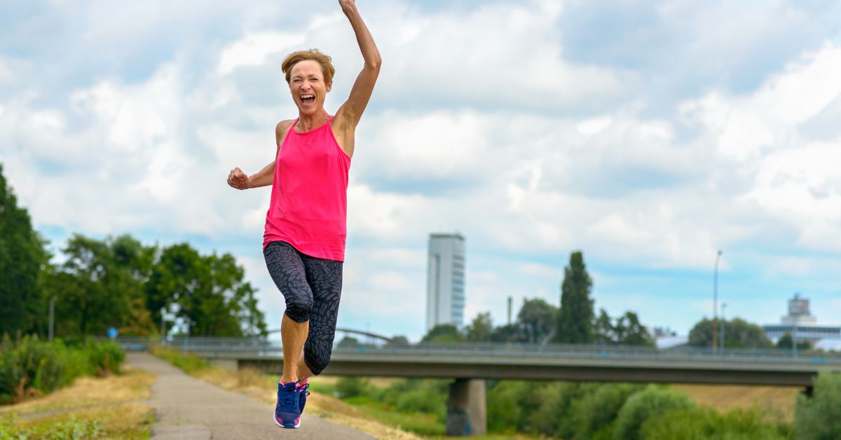 Active mature woman celebrating life and wellness in bright pink workout clothes